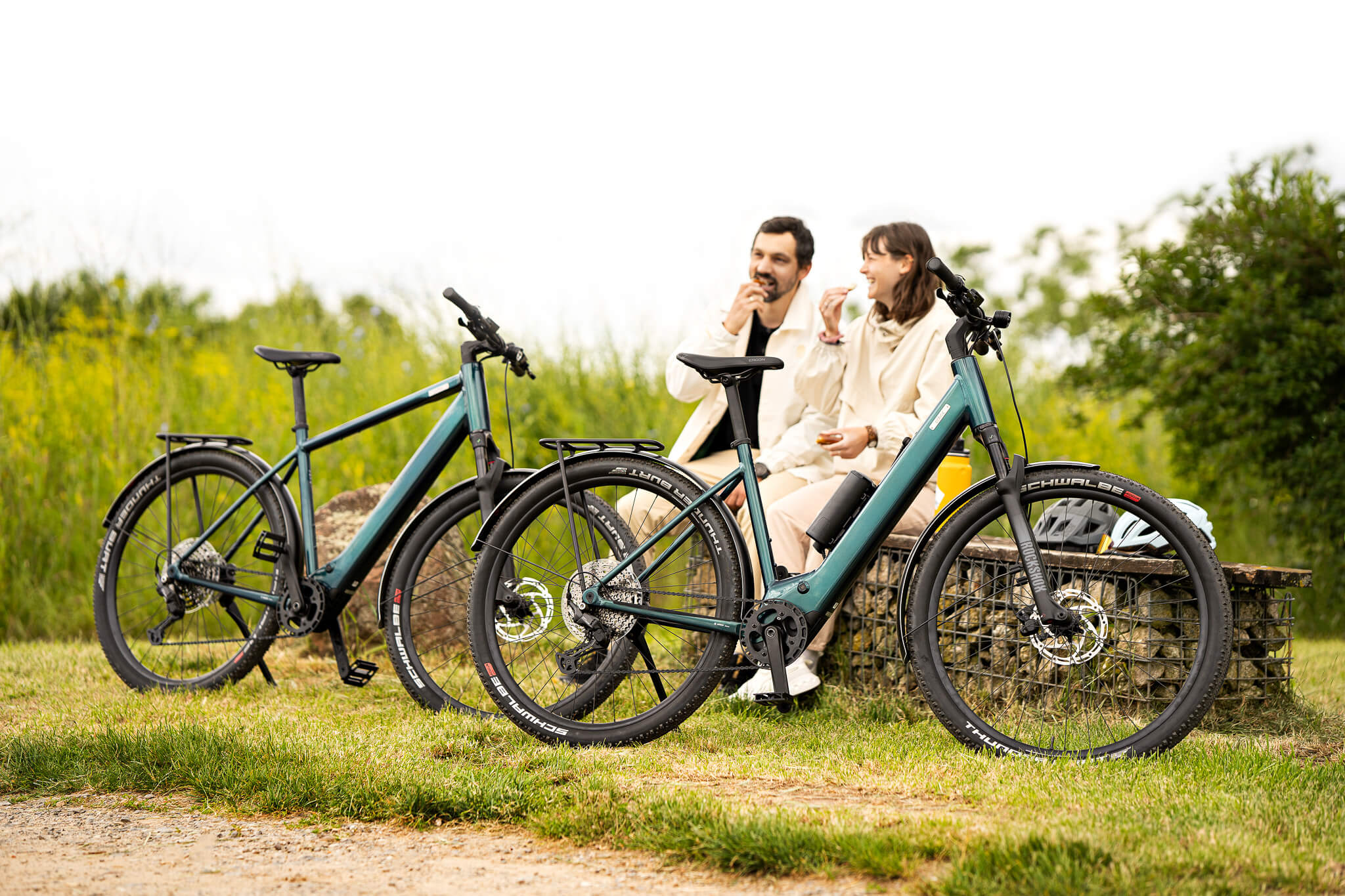 Mann und Frau sitzen neben Coboc E-Bikes mit Mittelmotor von Bosch Skye Step und Skye auf Bank